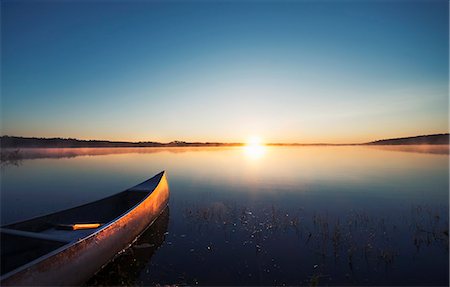 saskatchewan - A canoe on a flat calm lake at sunset. Foto de stock - Royalty Free Premium, Número: 6118-08023774