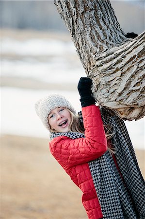 simsearch:6118-08023790,k - A young girl in a red jacket, and long scarf, gripping a tree trunk. Stock Photo - Premium Royalty-Free, Code: 6118-08023786