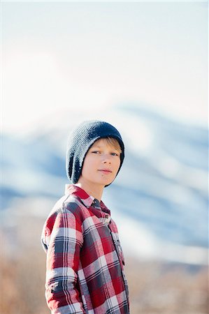 simsearch:6118-08023790,k - A boy with a woolly hat and checked shirt standing in open countryside in winter. Stock Photo - Premium Royalty-Free, Code: 6118-08023789