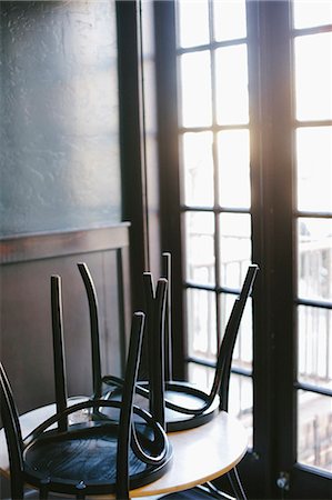 A table in a cafe with the chairs up, at the end of the day. Photographie de stock - Premium Libres de Droits, Code: 6118-08023793