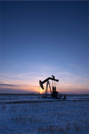pozo de petróleo - An oil drilling rig and pumpjack on a flat plain in the Canadian oil fields at sunset. Foto de stock - Sin royalties Premium, Código: 6118-08023709