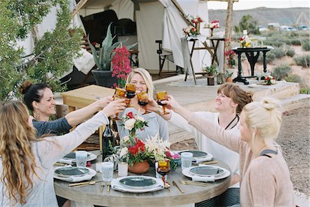 simsearch:6118-08883010,k - A group of women enjoying an outdoor meal by a large tent, in a desert landscape, raising a toast by clinking glasses. Stock Photo - Premium Royalty-Free, Code: 6118-08140156