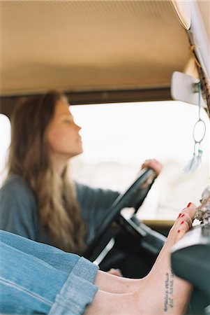 panel - Barefoot woman resting her feet on the dashboard of a 4x4, a tattoo on her right foot, another woman driving. Foto de stock - Sin royalties Premium, Código: 6118-08140173