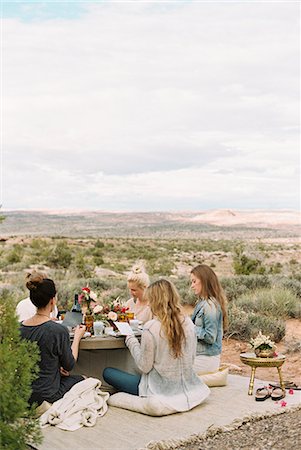 A group of women, friends sitting on the ground round a table in the open desert. Stock Photo - Premium Royalty-Free, Code: 6118-08140188
