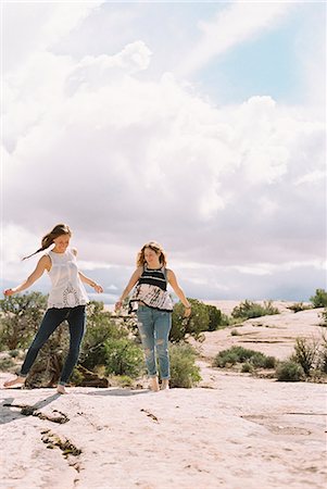 simsearch:6118-09165967,k - Two women running barefoot across the sand in a desert landscape Foto de stock - Sin royalties Premium, Código: 6118-08140195