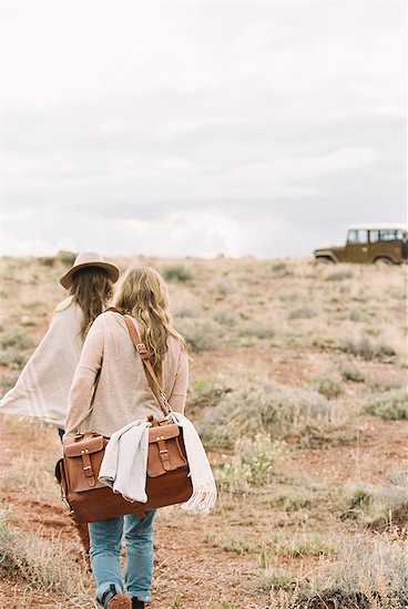 Two women walking towards a 4x4 parked in a desert. Stock Photo - Premium Royalty-Free, Image code: 6118-08140226