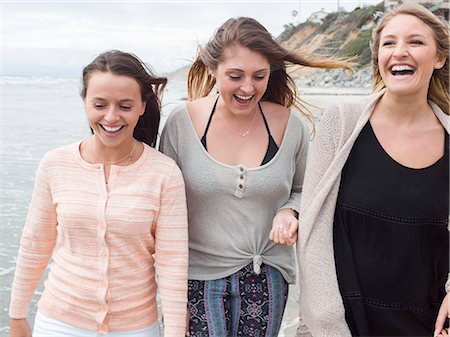 simsearch:6118-08129644,k - Three smiling young women walking on a beach. Fotografie stock - Premium Royalty-Free, Codice: 6118-08129643
