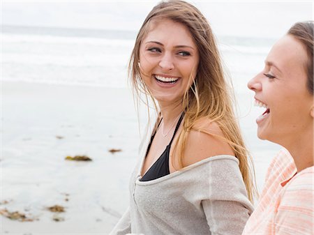 simsearch:6118-08129648,k - Two smiling young women walking on a beach. Photographie de stock - Premium Libres de Droits, Code: 6118-08129642