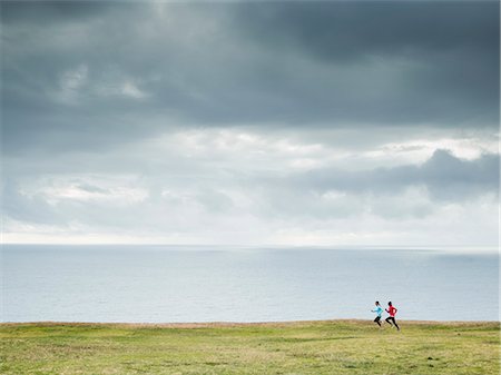 simsearch:6118-08129644,k - Two women jogging along the coast. Fotografie stock - Premium Royalty-Free, Codice: 6118-08129649