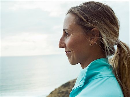 simsearch:6118-08129644,k - A smiling young woman, side profile, in a blue running top. Fotografie stock - Premium Royalty-Free, Codice: 6118-08129657