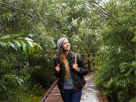 simsearch:6118-08129691,k - Smiling young woman walking through woodland in a park. Foto de stock - Sin royalties Premium, Código: 6118-08129662