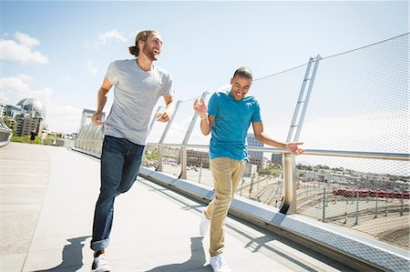 simsearch:6118-08129644,k - Two young men jogging along a bridge. Fotografie stock - Premium Royalty-Free, Codice: 6118-08129683
