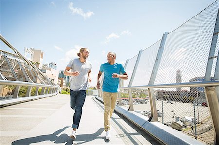 simsearch:6118-08129644,k - Two young men jogging along a bridge. Fotografie stock - Premium Royalty-Free, Codice: 6118-08129682