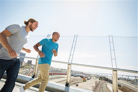 simsearch:6118-08129644,k - Two young men jogging along a bridge. Fotografie stock - Premium Royalty-Free, Codice: 6118-08129684