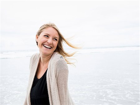 simsearch:6118-08129648,k - Portrait of a smiling young woman on a beach. Photographie de stock - Premium Libres de Droits, Code: 6118-08129699