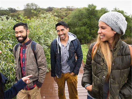 simsearch:6118-08129648,k - Smiling young woman and two young men walking in a park. Stock Photo - Premium Royalty-Free, Code: 6118-08129629