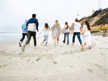 simsearch:6118-07203856,k - A group of young men and women running on a beach, having fun. Foto de stock - Royalty Free Premium, Número: 6118-08129704