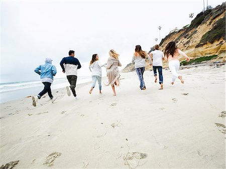 simsearch:6118-07203856,k - A group of young men and women running on a beach, having fun. Foto de stock - Royalty Free Premium, Número: 6118-08129705