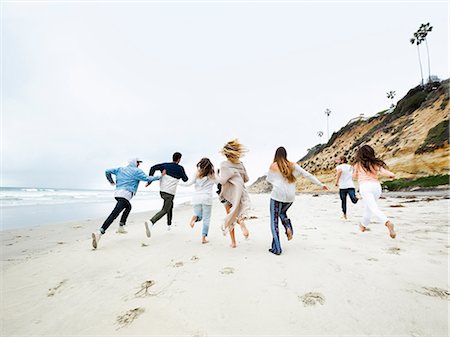 A group of young men and women running on a beach, having fun. Stock Photo - Premium Royalty-Free, Code: 6118-08129706