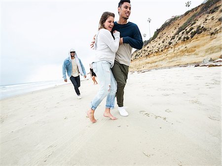 simsearch:6118-08129648,k - A group of young men and women running on a beach, having fun. Photographie de stock - Premium Libres de Droits, Code: 6118-08129708