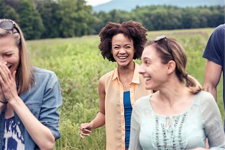 simsearch:6118-08220642,k - A group of women walking through a meadow in the countryside laughing. Fotografie stock - Premium Royalty-Free, Codice: 6118-08243784