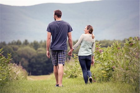 A couple, man and woman walking through a meadow holding hands. Stock Photo - Premium Royalty-Free, Code: 6118-08243791