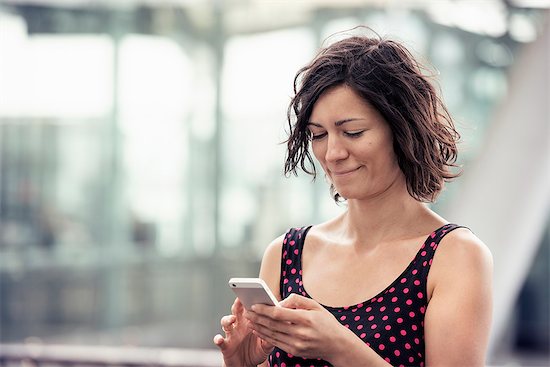 A woman on a street using her cell phone, checking for messages Photographie de stock - Premium Libres de Droits, Le code de l’image : 6118-08243854