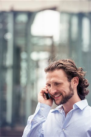 simsearch:6118-08243850,k - A man with a beard talking on a cell phone on a street in the city. Stock Photo - Premium Royalty-Free, Code: 6118-08243856