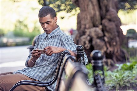 simsearch:6118-09129452,k - A man seated on a park bench using his smart phone Foto de stock - Sin royalties Premium, Código: 6118-08243801