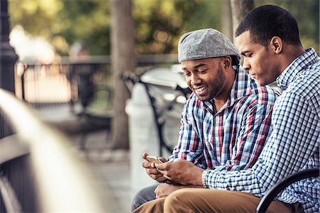 Two men sitting in a park, looking at a smart phone Photographie de stock - Premium Libres de Droits, Code: 6118-08243812