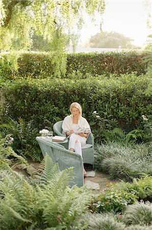 Blond woman sitting in a wicker chair in a garden. Stock Photo - Premium Royalty-Free, Code: 6118-08282245