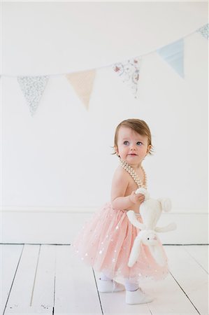 salmon pink - Young girl holding a cuddly toy, standing in a photographers studio, posing for a picture. Stock Photo - Premium Royalty-Free, Code: 6118-08282285
