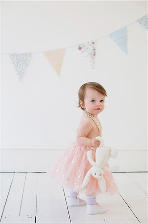 Young girl holding a cuddly toy, standing in a photographers studio, posing for a picture. Stock Photo - Premium Royalty-Free, Code: 6118-08282286