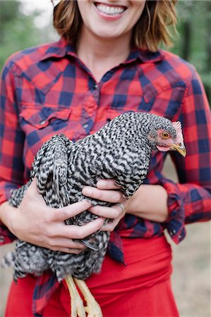 red - Portrait of a smiling woman holding a grey specked hen. Stock Photo - Premium Royalty-Free, Code: 6118-08282226