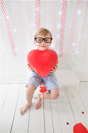 shorts and pants - Young boy posing for a picture in a photographers studio, holding red balloons. Stock Photo - Premium Royalty-Free, Code: 6118-08282312