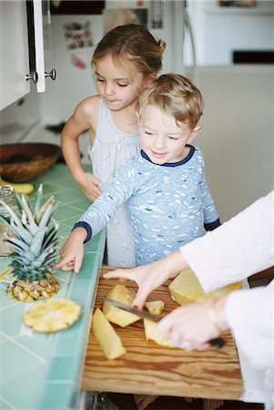 simsearch:656-02702879,k - Woman cutting a fresh pineapple for her children. Photographie de stock - Premium Libres de Droits, Code: 6118-08202482