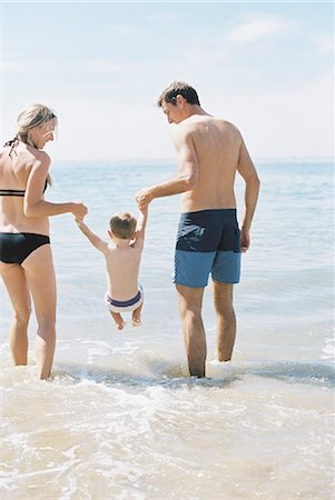 simsearch:6118-08659802,k - Couple playing with their son on a sandy beach by the ocean. Stock Photo - Premium Royalty-Free, Code: 6118-08202486
