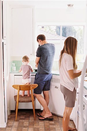 simsearch:6118-08659802,k - Couple standing in a kitchen, their son standing on a chair beside them. Stock Photo - Premium Royalty-Free, Code: 6118-08202499