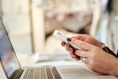 A woman using a laptop and a smart phone, making calls, running a business. Stock Photo - Premium Royalty-Free, Code: 6118-08202522