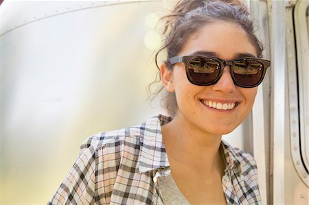 A young woman wearing sunglasses by a silver coloured trailer. Foto de stock - Royalty Free Premium, Número: 6118-08220568