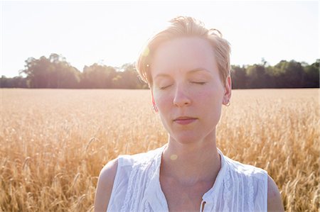 simsearch:6113-08220455,k - Head and shoulders portrait of a young woman standing in a cornfield. Stock Photo - Premium Royalty-Free, Code: 6118-08220581