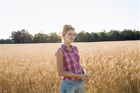 simsearch:6118-08220592,k - Young woman wearing a checked shirt standing in a cornfield. Stockbilder - Premium RF Lizenzfrei, Bildnummer: 6118-08220582