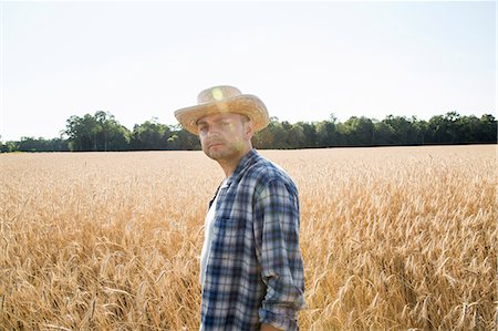 sustainability - Man wearing a checked shirt and a hat standing in a cornfield, a farmer. Stock Photo - Premium Royalty-Free, Code: 6118-08220585