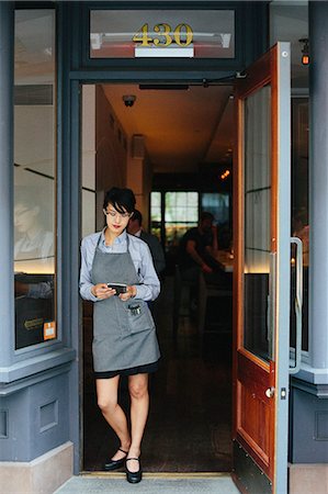 small business phone outside - Young waitress wearing an apron at a city restaurant. Stock Photo - Premium Royalty-Free, Code: 6118-08226893