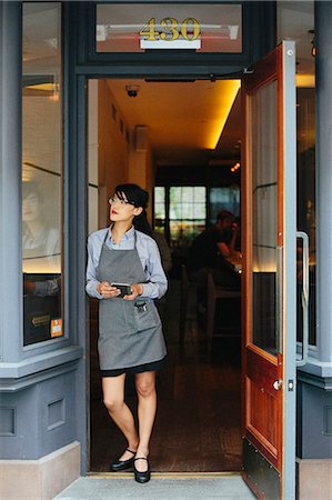 small business phone outside - Young waitress wearing an apron at a city restaurant. Stock Photo - Premium Royalty-Free, Code: 6118-08226894