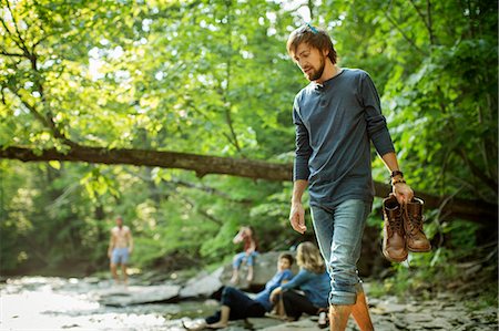 rolled up jeans - A man carrying his boots walking on the rocks by a river. Foto de stock - Sin royalties Premium, Código: 6118-08226964