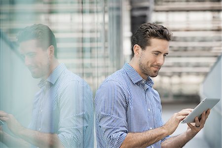 simsearch:6118-08351860,k - A man standing outside a building with large glass exterior panels, using a digital tablet. Stock Photo - Premium Royalty-Free, Code: 6118-08351883