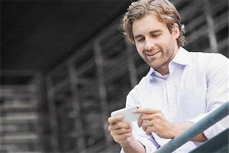 simsearch:6118-08351860,k - A man standing by a railing in a city, checking his smart phone. Stock Photo - Premium Royalty-Free, Code: 6118-08351890