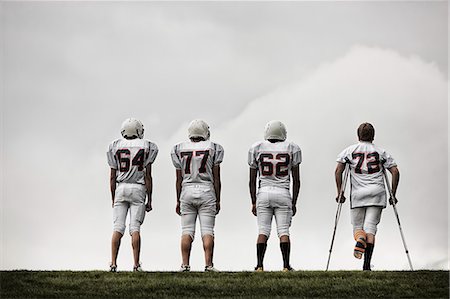 simsearch:614-08031104,k - A group of football players, young people in sports uniform and protective helmets. One person using crutches. Foto de stock - Sin royalties Premium, Código: 6118-08351827