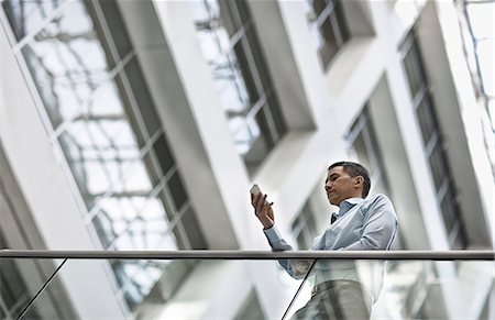 simsearch:6118-08351887,k - A man checking his smart phone in a large airy building with windows. Stockbilder - Premium RF Lizenzfrei, Bildnummer: 6118-08351943